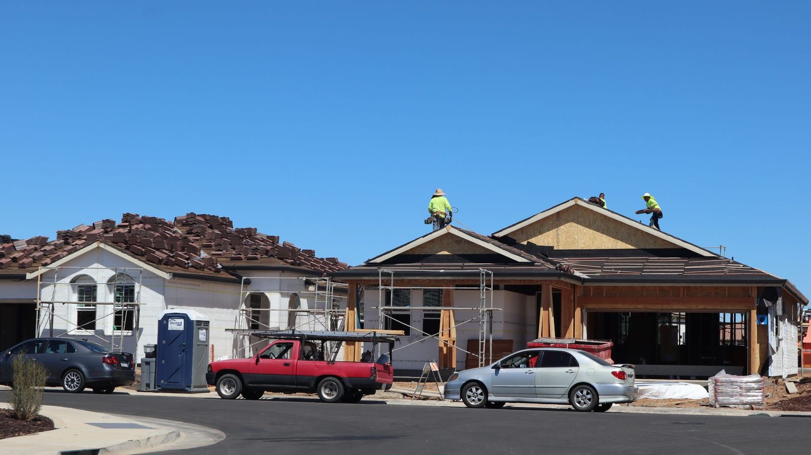 Roofers working on the roof of a new suburban house